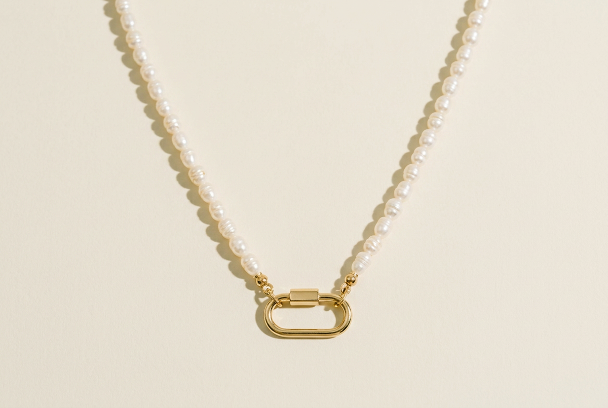 Freshwater pearl necklace with gold carabiner clasp and no charm on a cream background